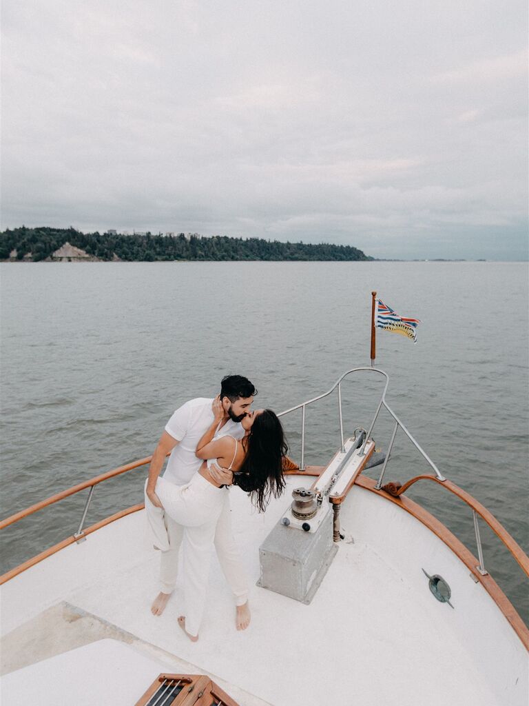 The happy couple kiss on a yacht in this engagement photo