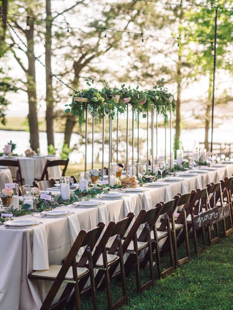 long outdoor wedding reception table with mixed high and low greenery centerpieces