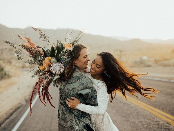 Couple hugging in the desert and holding bouquet