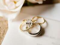 solitaire oval cut engagement ring on yellow gold band with matching wedding rings and silver men's wedding band