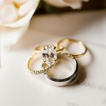 solitaire oval cut engagement ring on yellow gold band with matching wedding rings and silver men's wedding band