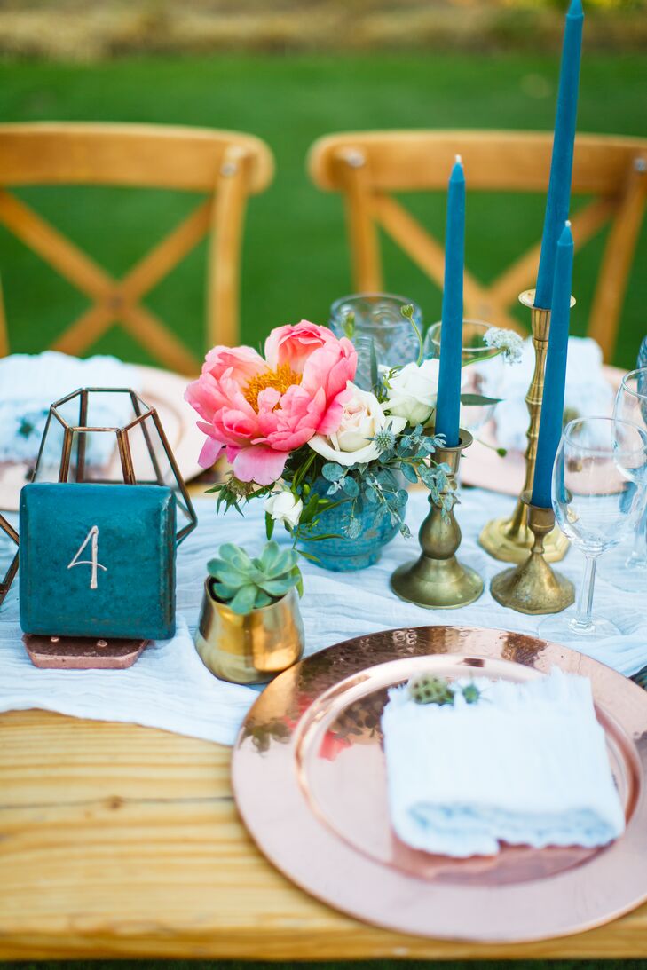 Wooden farm tables were topped with light blue runners, rose gold chargers, blue goblets, taper candles, succulents, blooms and terrariums. “The blue vintage water goblets and blue taper candles were just some of my favorite parts of the table decor," Taylor says. "They added that extra pop of color I was looking for.”