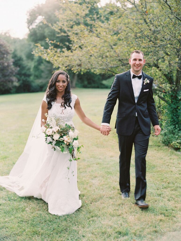 Couple walk hand in hand at an outdoor wedding ceremony. 