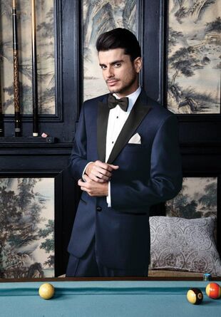 man wearing midnight blue tuxedo behind a pool table