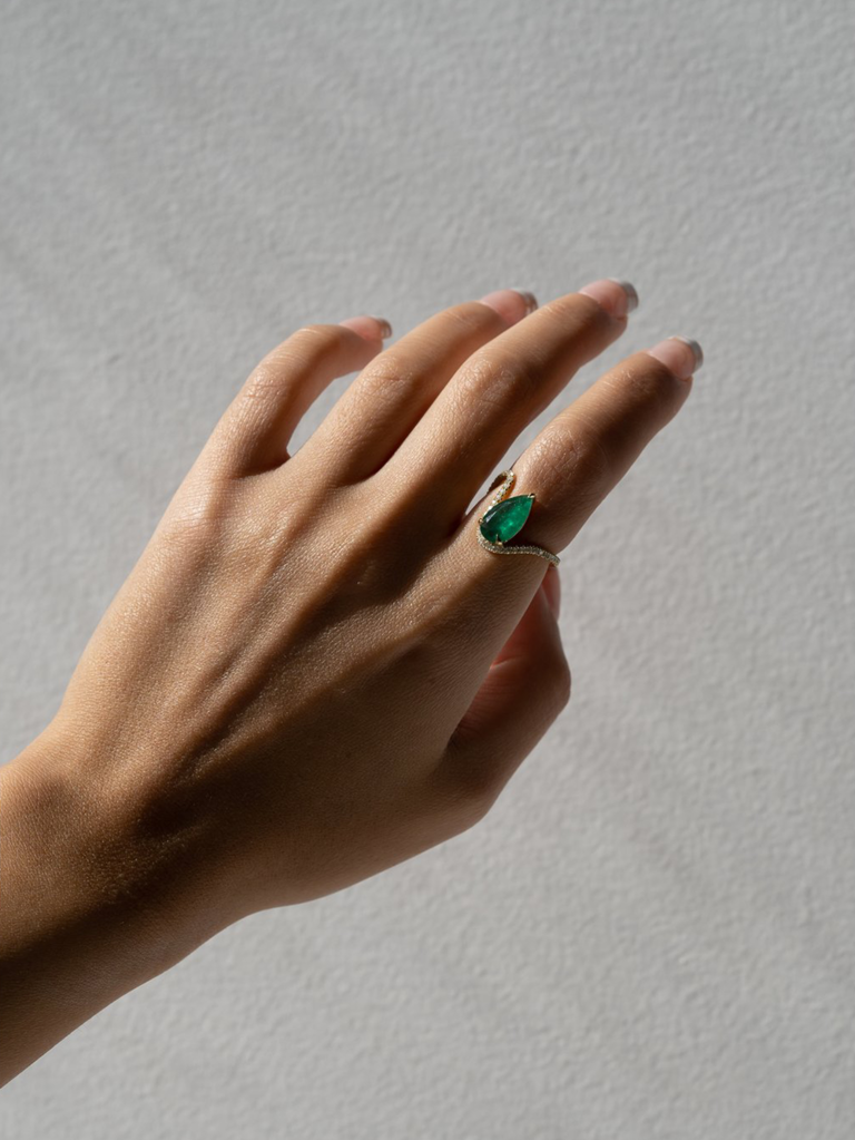 Floating pear emerald center stone with pave diamonds on wavy thin gold band