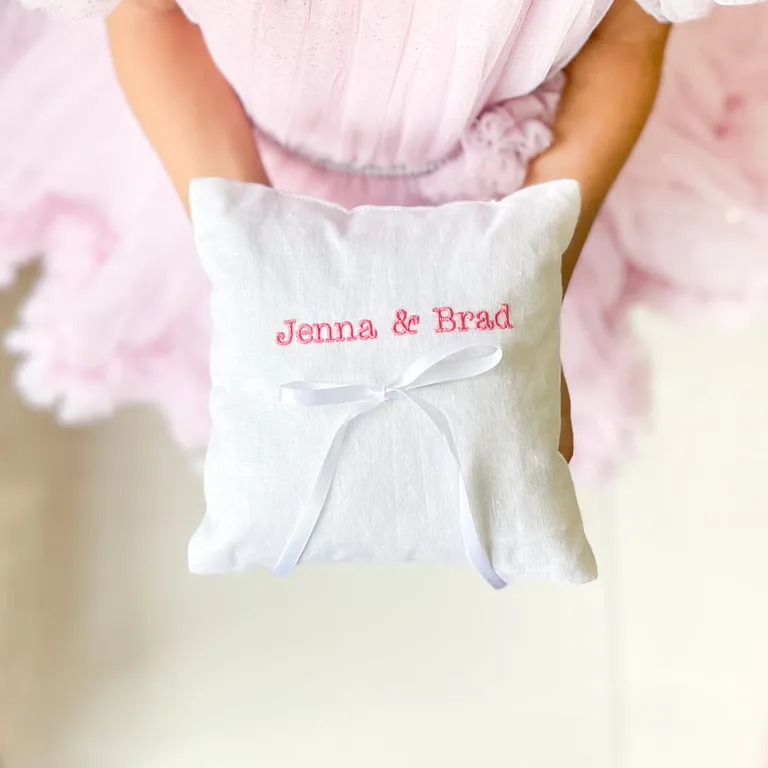 White linen ring bearer pillow with pink embroidered couples name