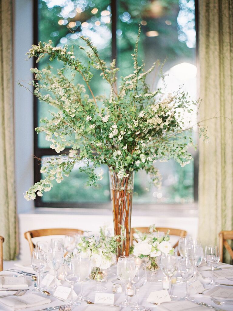 classic greenery wedding centerpiece with white lilac branches in glass vase