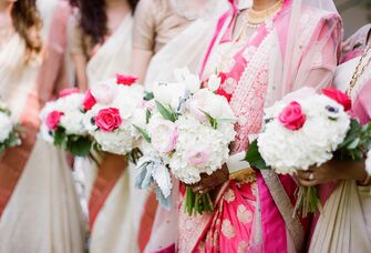 Bridesmaids and a bride holding white and pink bouquets.