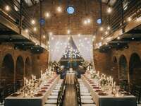 Rusing wedding reception venue with hanging bulb lights and tables with candles and flowers