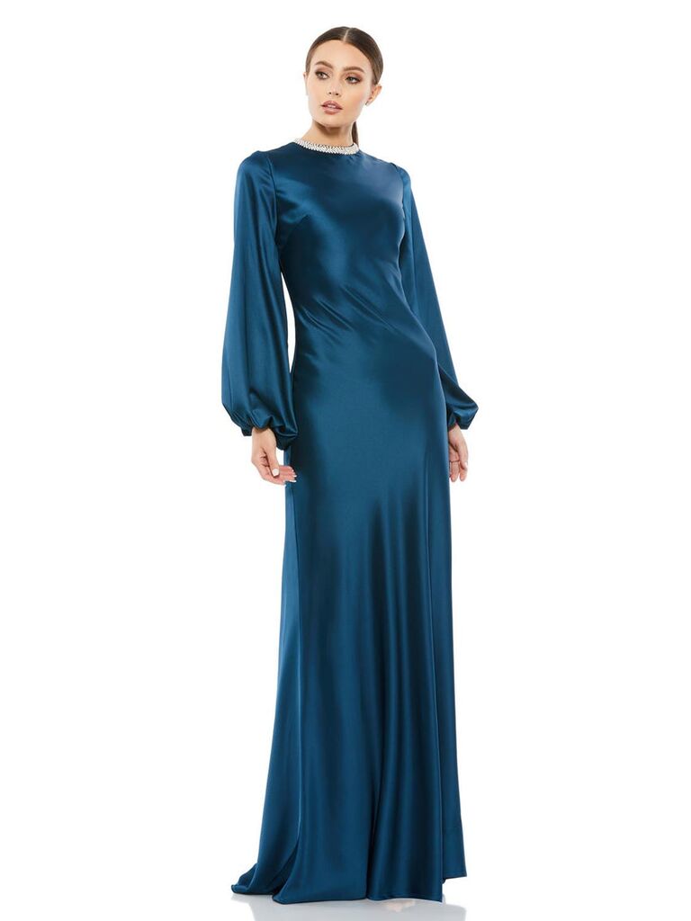Model wearing a sapphire gown with a detailed high neckline and long sleeves