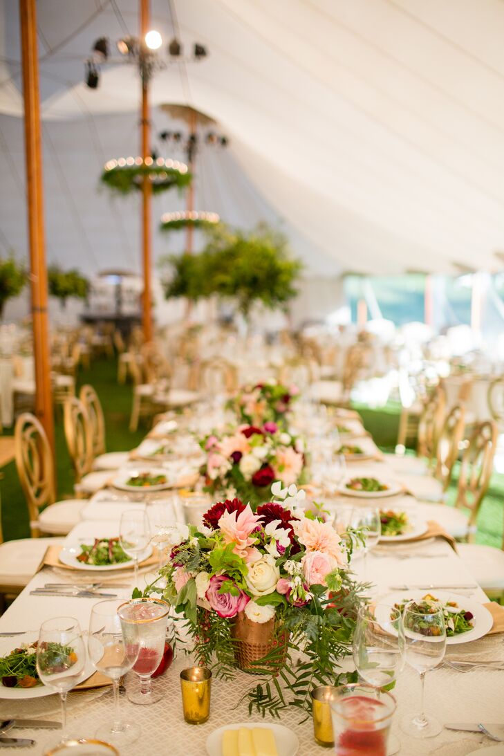 Centerpieces were a mix of tall vases filled with just greenery and more restrained arrangements of ivory garden roses, ranunculus and purple dahlias in petite vases.