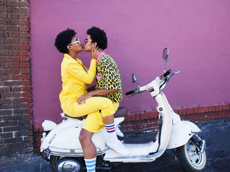 A couple kiss on the back of a Vespa.