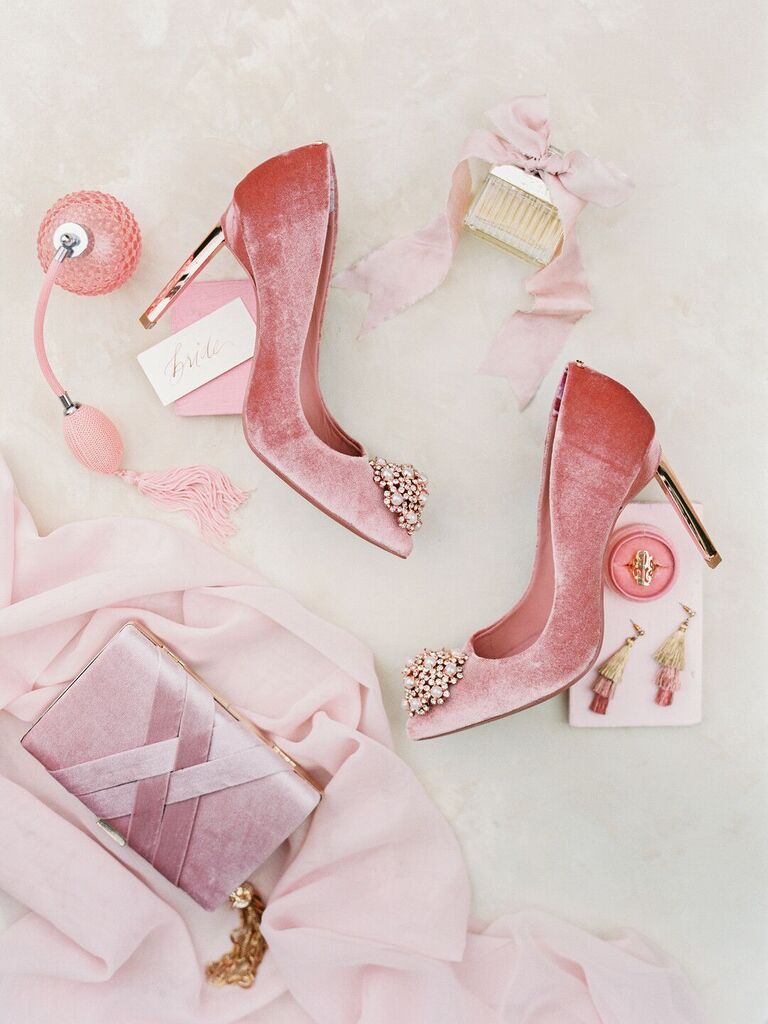 styled wedding flat lay with blush velvet stiletto heels, satin box clutch, chloe perfume bottle, and pink tassel earrings