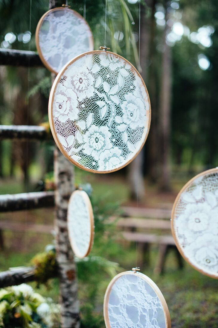 To add a romantic, vintage-inspired touch to their ceremony decor, the couple hung lace panels set in cross stitch hoops from the handcrafted birch ceremony arch.