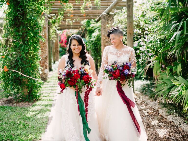 LGBTQ+ brides holding hands and walking in garden