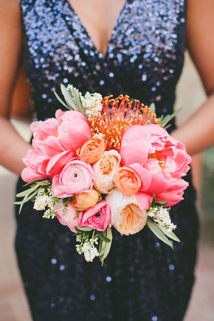 Fully bloomed peonies and protea added and depth and texture to the bridesmaids' cheerful pink, orange and peach bouquets.