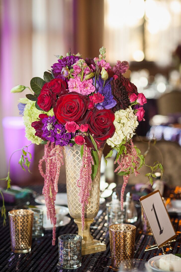 Cassandra wanted to have flowers other than white, so they filled gold vases with a combination of mostly red, purple and pink flowers—ranging from roses to hydrangeas and amaranthus that draped from the arrangement. The flowers decorated the middle of dining tables at the reception.