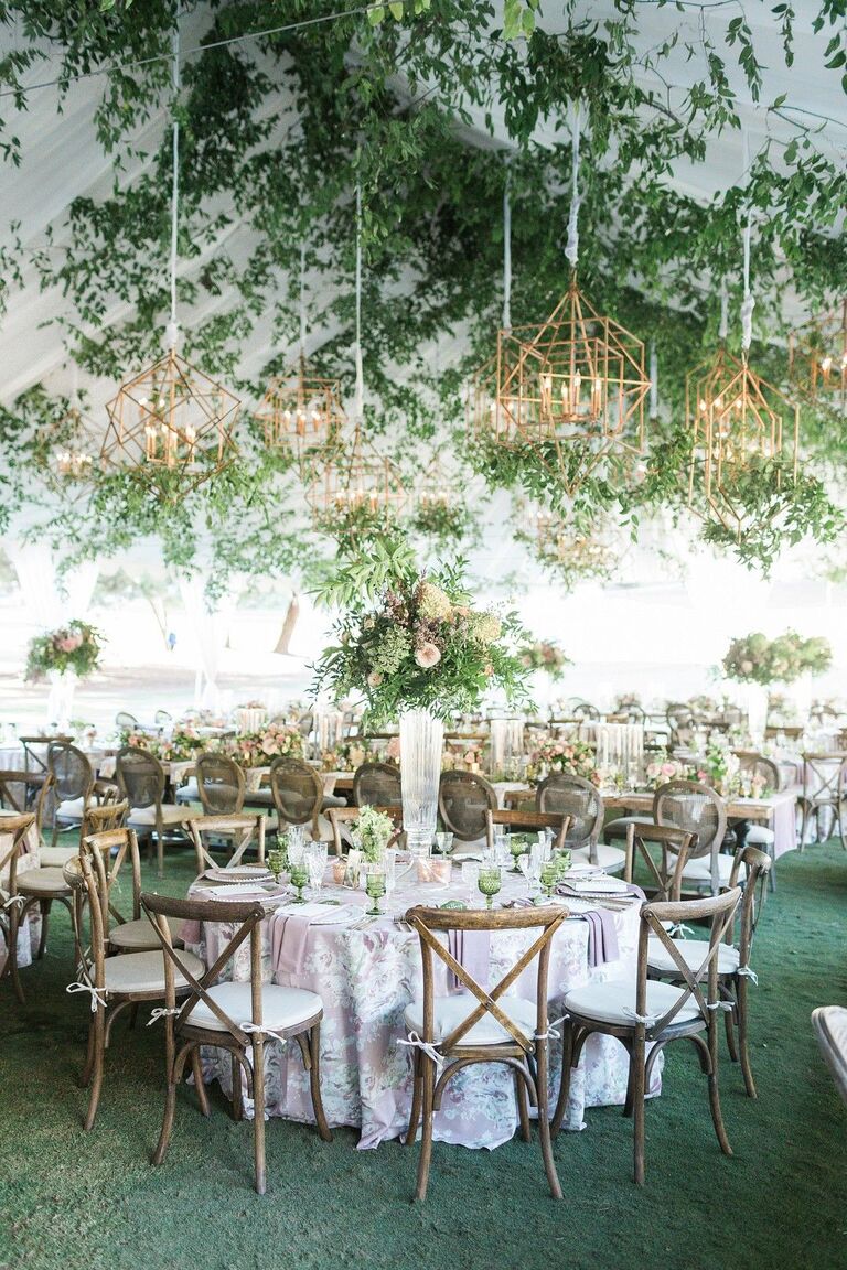 Romantic garden-inspired tented reception with gold chandeliers and cross-back chairs