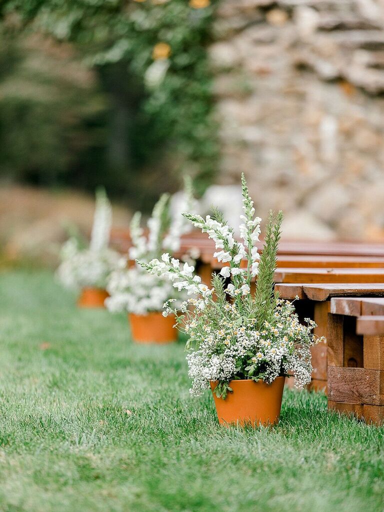 Potted wildflower plants along wedding ceremony aisle at outdoor wedding
