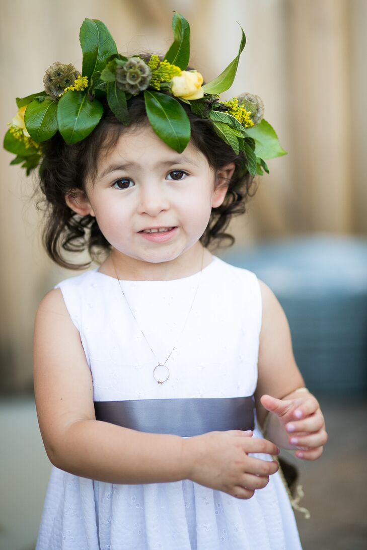 Their adorable flower girl wore a boho-chic flower crown made up of leafy greens, yellow roses and scabiosa pods. The hair accessory added a nice natural touch to her white and gray ensemble.