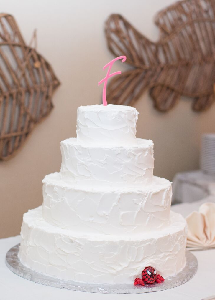 To give their wedding cake a fun personal touch, the couple added a Spiderman decoration and a pink "F" cake topper to the simple buttercream wedding cake.