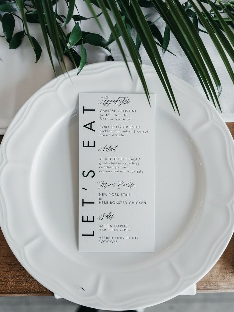 simple wedding place setting with white dinner plate and black and white menu card
