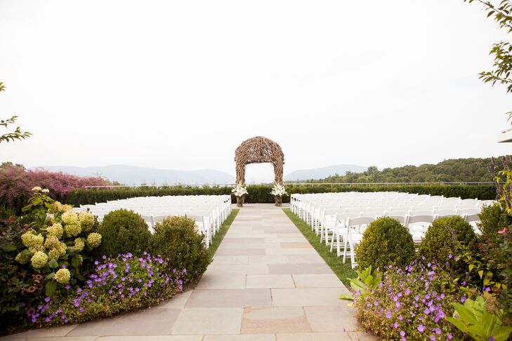 “While we were looking at venues, I knew I wanted to get married outside,” Kelley says. “Once I saw the ceremony garden at the Garrison, I knew this was going to be the place we say 'I do.' It has a mix of country and elegance, which was exactly what I wanted.” With this in mind, they focused on minimal added decor—except this incredible wooden arbor! About 180 chairs led the way to their ceremony space, while greenery, natural green hydrangeas and little purple flowers marked the entrance.