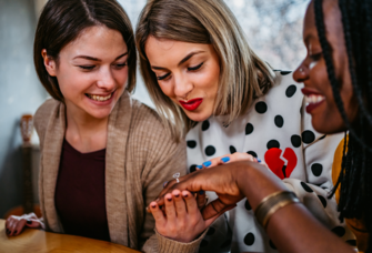Three friends looking at engagement ring