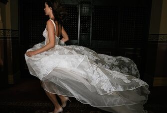 Model runs while a white floral wedding gown billows behind her. 