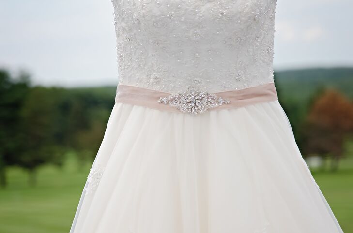 Mariel wore a David Tutera ball gown wedding dress with a beaded bodice and silver embroidered tulle skirt. She loved how her dress shimmered when the light hit it. Wanting to add a little more glamorous sparkle, she added a champagne belt around her waist that was accented with a gorgeous floral crystal broach.