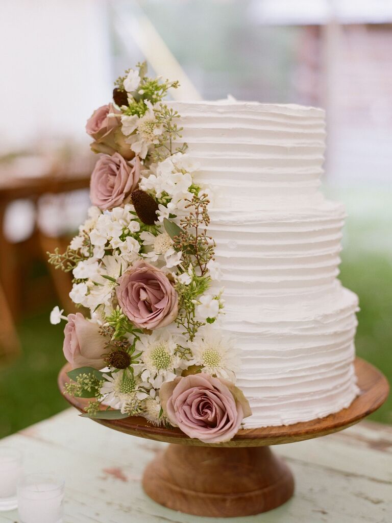 three-tier white buttercream wedding cake with mauve roses, white flowers and eucalyptus