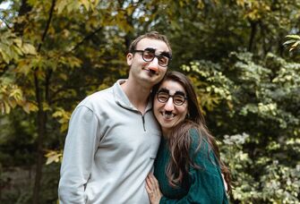 Couple poses for the camera wearing funny glasses. 