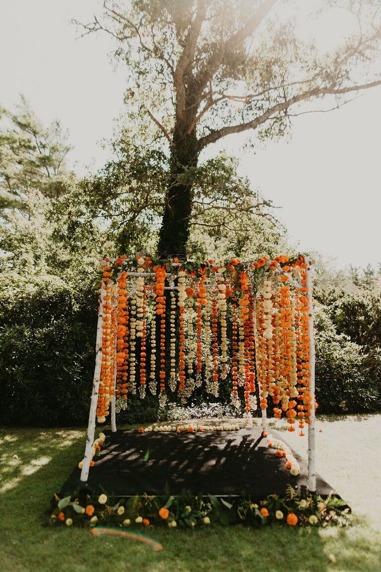 Rustic mandap with orange flower garlands