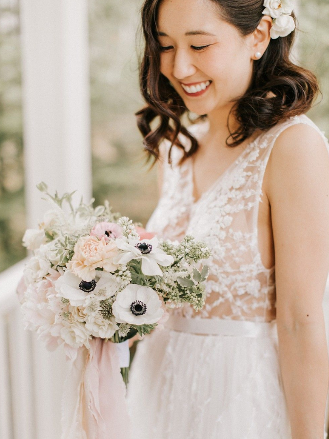 Bride holding anemone bouquet and smiling