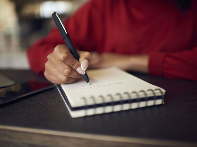 Woman writing in notebook financial planning for wedding