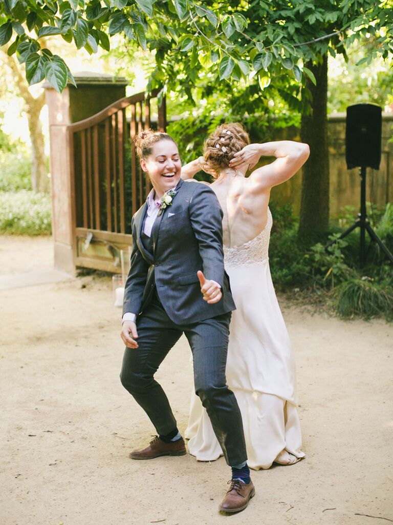 Same sex couple enthusiastically dancing to first dance song at wedding reception