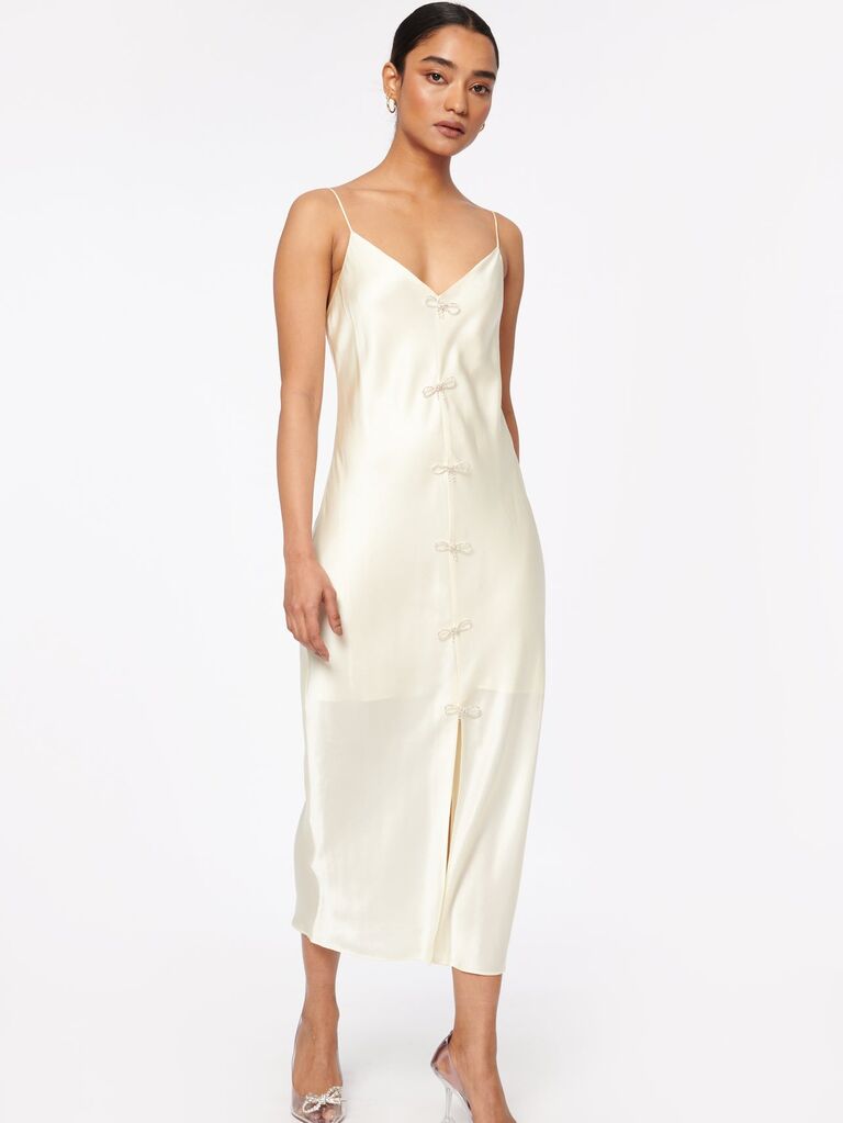 Model wears a chic silk slip dress with bows down the front. 