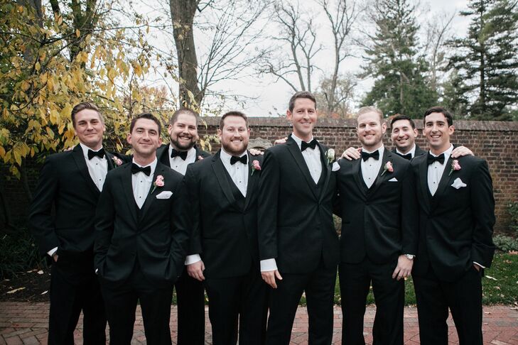David and his groomsmen wore classic black tuxedos and bow ties from Black by Vera Wang. David wore a white rose boutonniere to distinguish himself from his groomsmen, who wore pink rose boutonnieres.