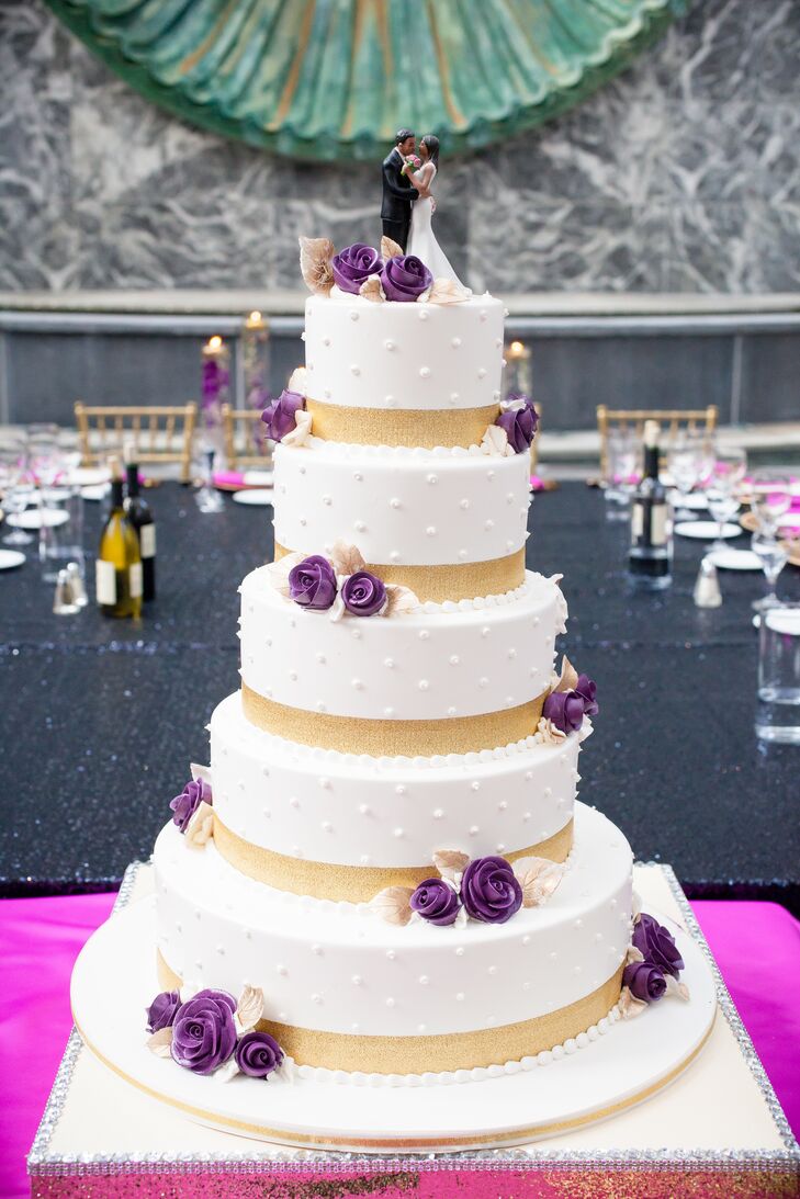 The five-tier wedding cake featured gold stripes and purple flowers and sat atop a glittery gold stand.