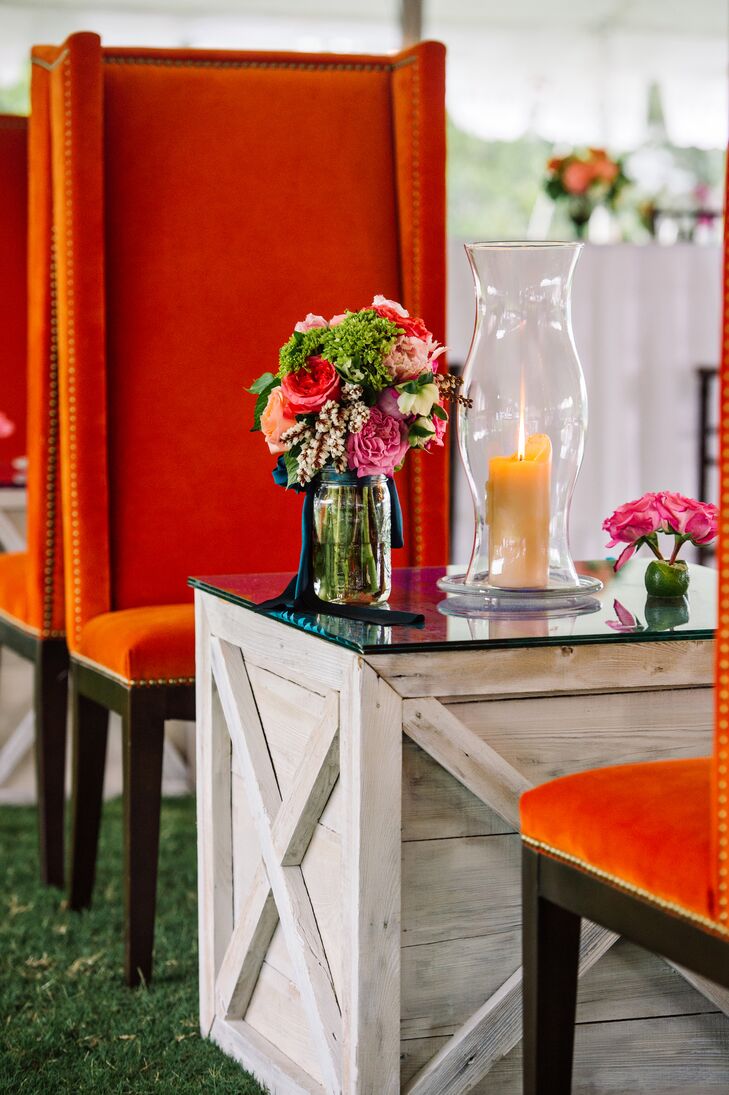 The lounge furniture came with its own romantic centerpieces. Each glass-topped table was paired with a low arrangement of pink roses inside a lime. Tall candles in trumpet glass vases as well as natural arrangements of mini green hydrangeas, bright garden roses and wax flowers from Events by Nouveau made the seating stand out.