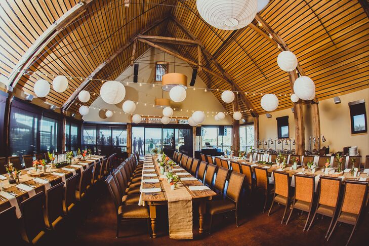 The reception was held inside the barn at Brasada Ranch. White paper lanterns hung above long wood dining tables with brown draped table runners.