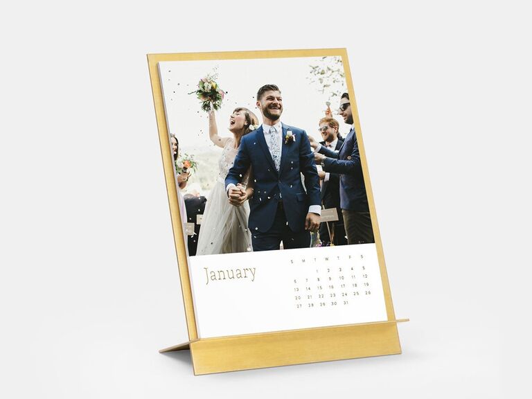 Gold calender gift displays a photo of a couple at their wedding. 