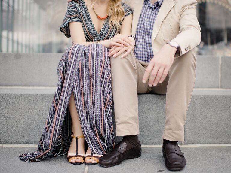 Engaged couple sitting on cement steps.