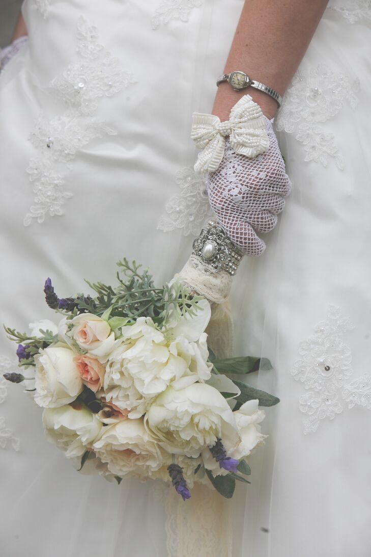 Jessica carried an elegant bouquet of white cabbage roses (similar to peonies), coral garden roses, dahlias, lamb's ear, baby's breath, and lavender, which was arranged by her aunt. She accessorized her vintage look with a pair of lavender lace gloves with large white bows, which she found on Etsy.