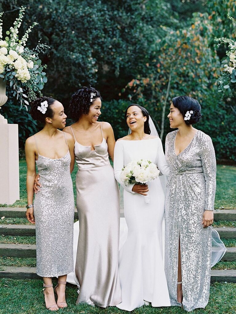 Bridesmaids wear silver sparkling gowns. 