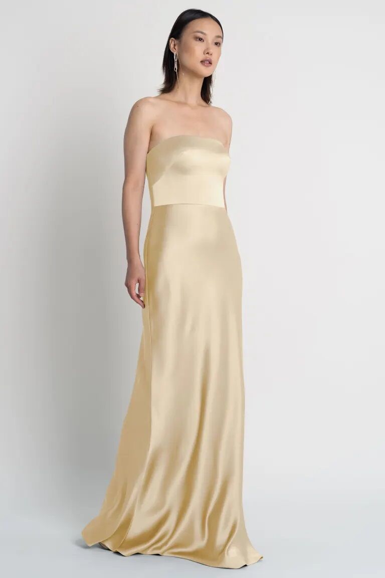 Model wears a strapless silk gown in a pale yellow color. 