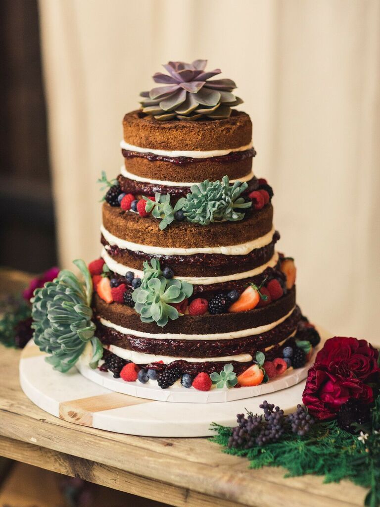 three tier chocolate naked wedding cake decorated with green and purple succulents and fresh berries
