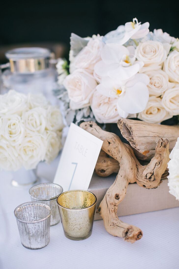 Table settings were made with driftwood, sea glass, candles and white roses.