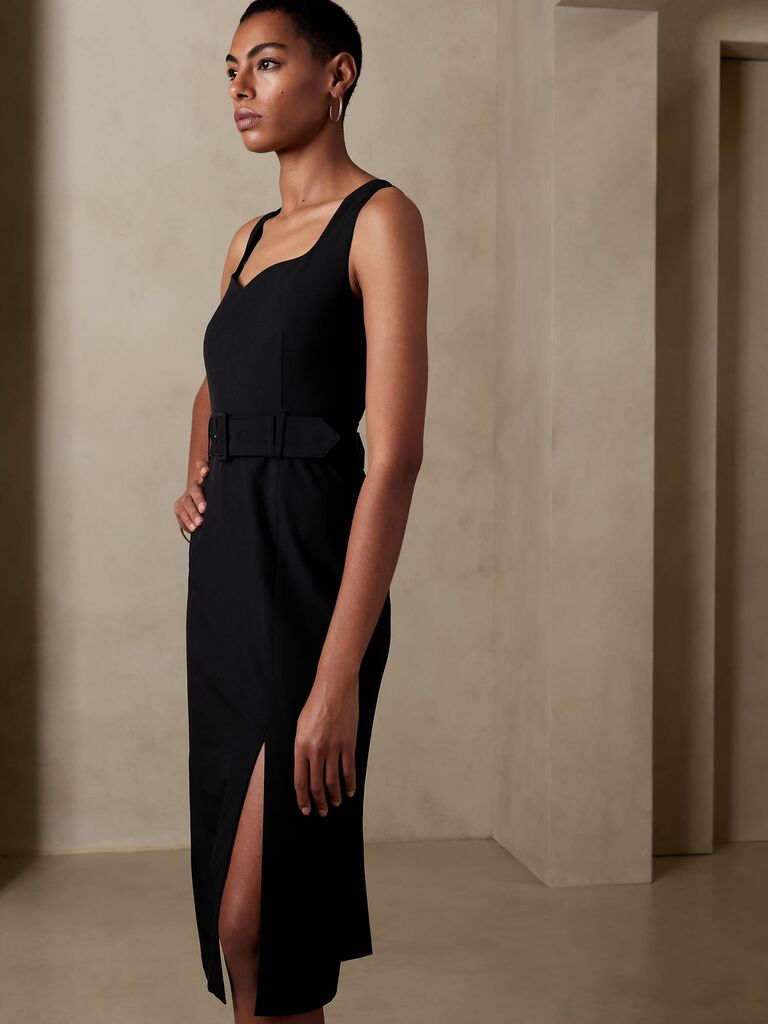 Model wearing a sheath midi dress in black with a belt