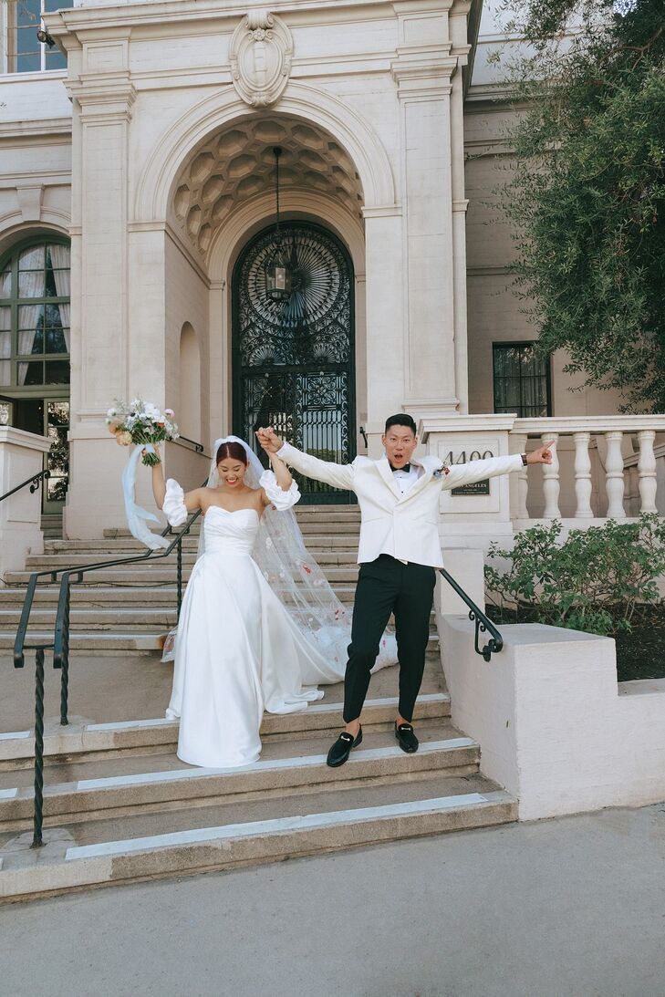 Bride in Sleek A-Line Dress, Floral Veil and Groom in White-and-Black Suit